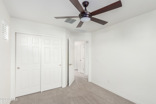 unfurnished bedroom with light colored carpet, a closet, and ceiling fan