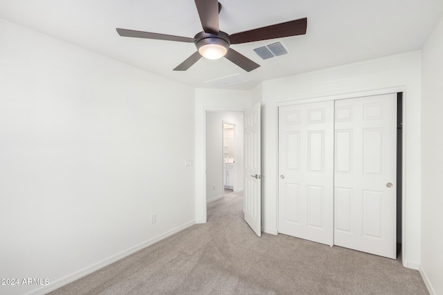 unfurnished bedroom featuring light colored carpet, a closet, and ceiling fan