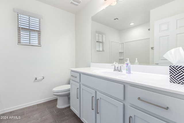 bathroom with toilet, a shower, vanity, and wood-type flooring