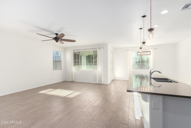 unfurnished living room featuring sink, light hardwood / wood-style flooring, and a healthy amount of sunlight