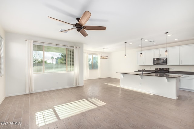 kitchen with light hardwood / wood-style flooring, white cabinetry, stainless steel appliances, and decorative light fixtures