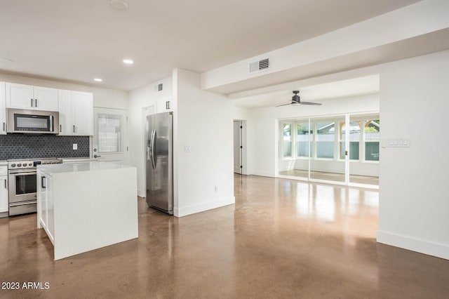 kitchen with concrete flooring, white cabinetry, decorative backsplash, a center island, and stainless steel appliances