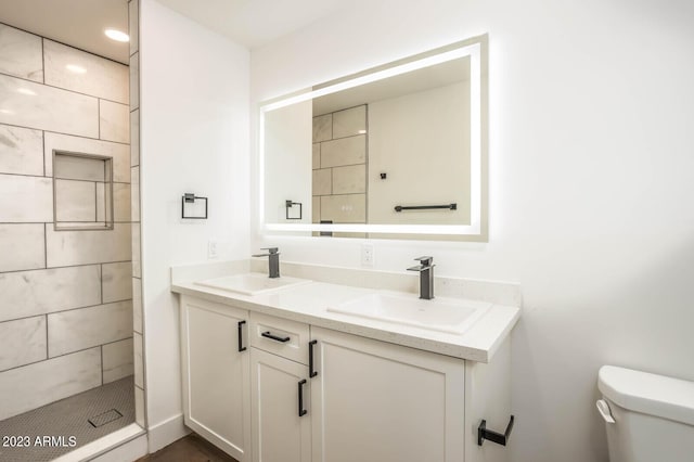 bathroom with vanity, tiled shower, and toilet