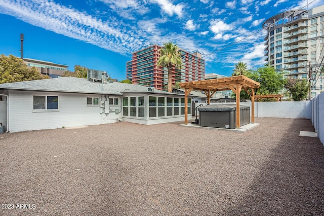 rear view of property with a hot tub, a pergola, and a sunroom