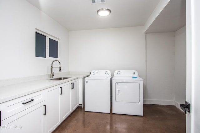 clothes washing area featuring cabinets, sink, and independent washer and dryer