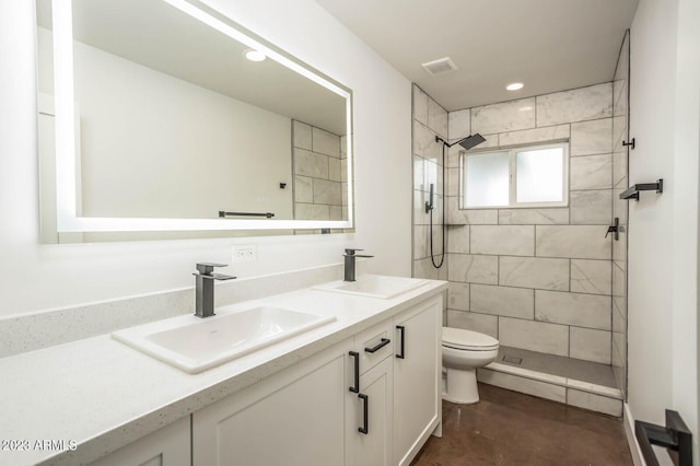 bathroom with vanity, concrete flooring, toilet, and tiled shower