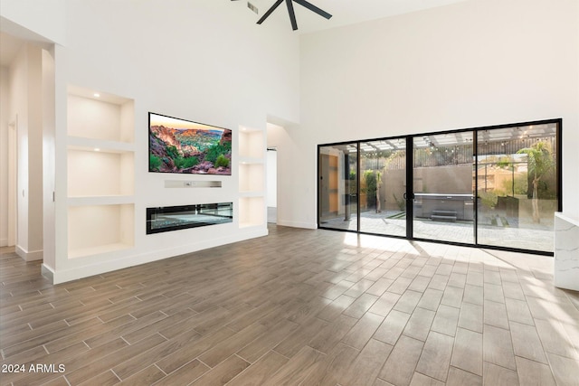 unfurnished living room with a towering ceiling and built in features