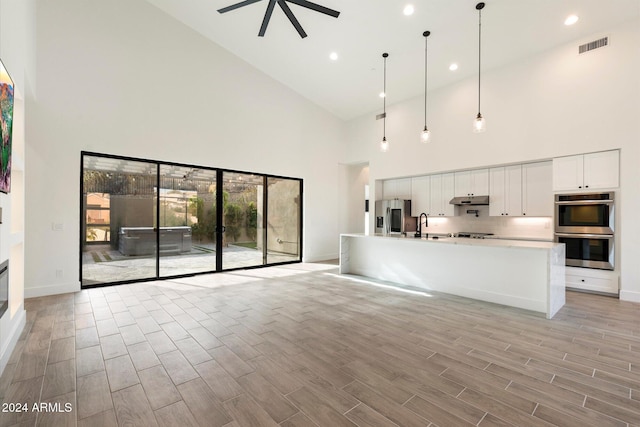 unfurnished living room featuring ceiling fan and a towering ceiling