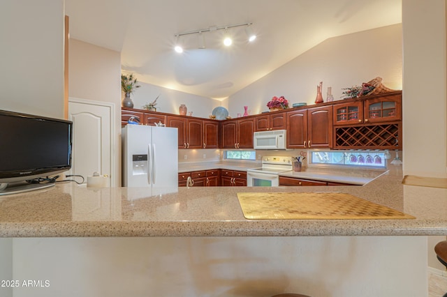 kitchen featuring light stone countertops, lofted ceiling, white appliances, and kitchen peninsula