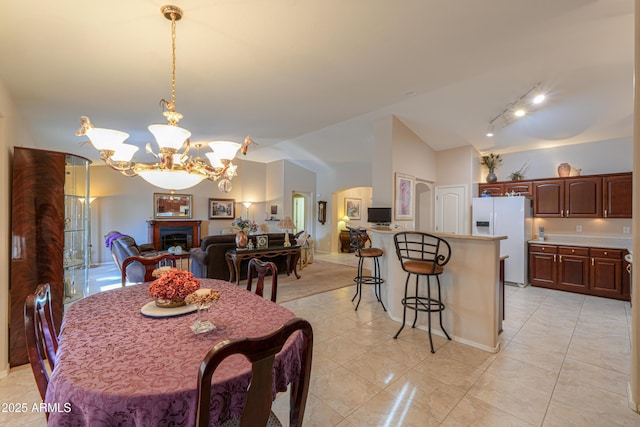 dining area with track lighting, a chandelier, and vaulted ceiling