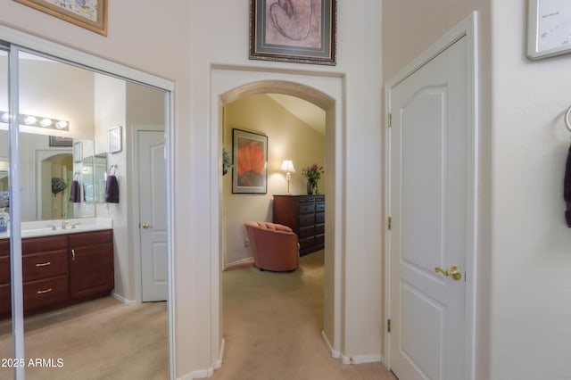 hall with sink and light colored carpet