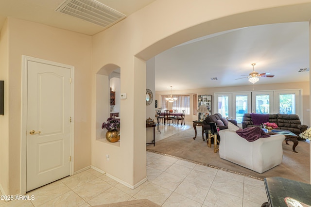 tiled living room with a healthy amount of sunlight and ceiling fan with notable chandelier