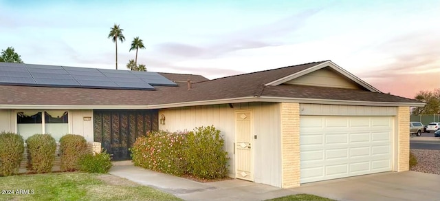 ranch-style home with a garage and solar panels