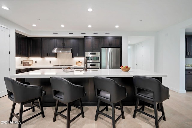 kitchen with dark brown cabinets, a large island, appliances with stainless steel finishes, and a kitchen breakfast bar