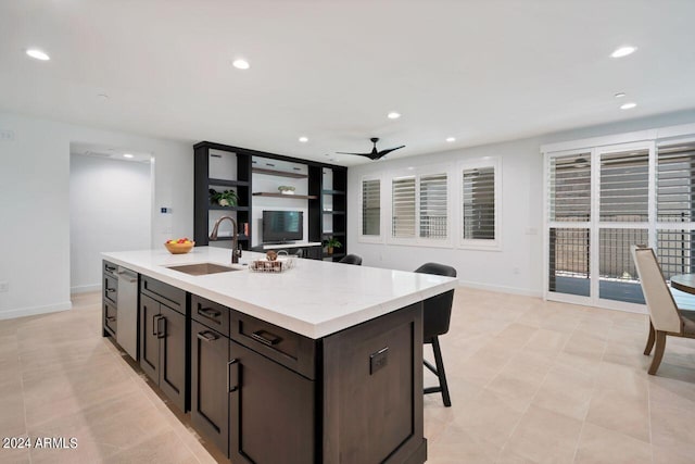 kitchen featuring dark brown cabinets, sink, an island with sink, a kitchen breakfast bar, and ceiling fan