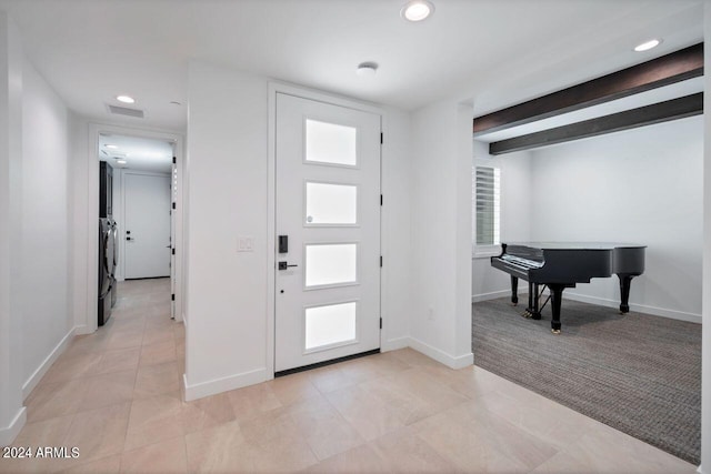 foyer featuring light tile patterned floors, beam ceiling, and washer and dryer