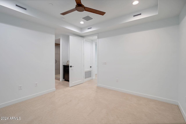 carpeted spare room with ceiling fan and a raised ceiling