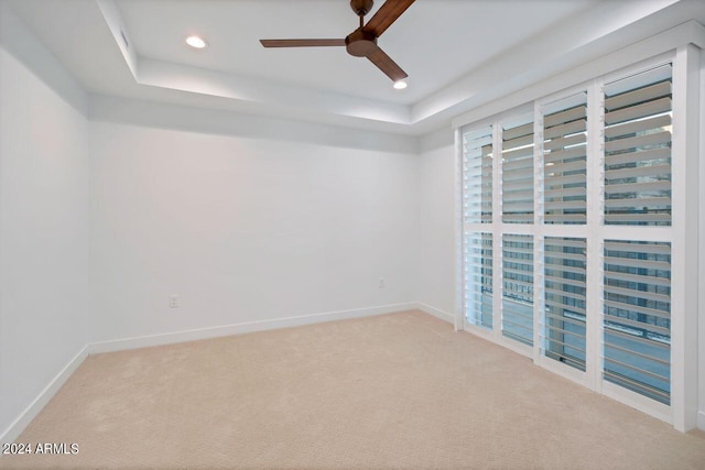 unfurnished room featuring ceiling fan, a tray ceiling, and carpet flooring