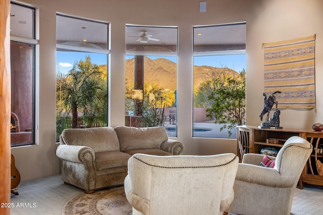 living area featuring light carpet, a mountain view, and a ceiling fan