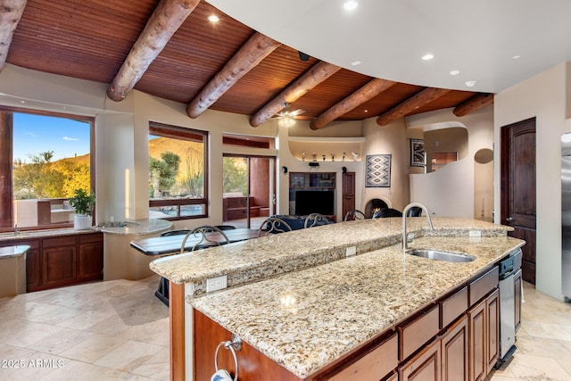 kitchen featuring a spacious island, wood ceiling, open floor plan, light stone countertops, and a sink