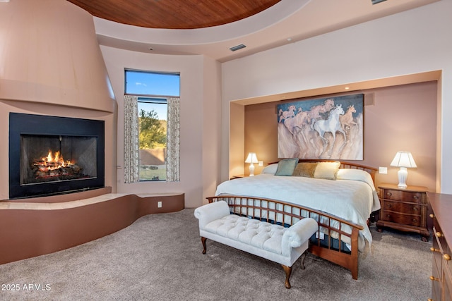 carpeted bedroom with wood ceiling, a raised ceiling, and a fireplace