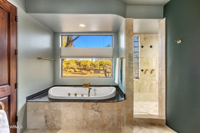 full bathroom featuring a tub with jets, a tile shower, and tile patterned floors