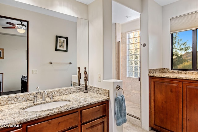 full bathroom featuring a stall shower, ceiling fan, two vanities, and a sink