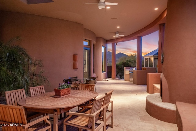 view of patio / terrace with exterior kitchen, outdoor dining space, ceiling fan, and a mountain view