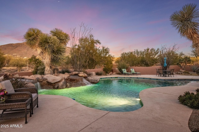 pool at dusk with a patio, fence, and a fenced in pool