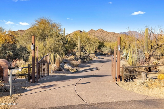 view of road featuring driveway, a gate, a mountain view, and a gated entry