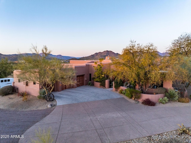 southwest-style home with driveway, a mountain view, and stucco siding