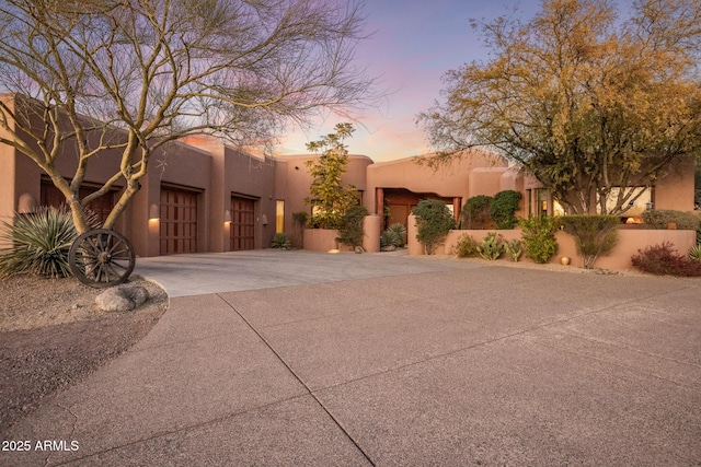 southwest-style home featuring driveway, an attached garage, and stucco siding