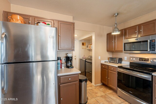 15211 N 89th Ave, Peoria, AZ 85381 - kitchen with appliances with stainless steel finishes, light countertops, independent washer and dryer, light tile patterned floors, and pendant lighting