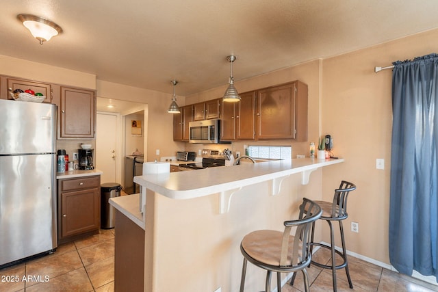 15211 N 89th Ave, Peoria, AZ 85381 - kitchen featuring appliances with stainless steel finishes, a kitchen breakfast bar, light countertops, a peninsula, and light tile patterned floors