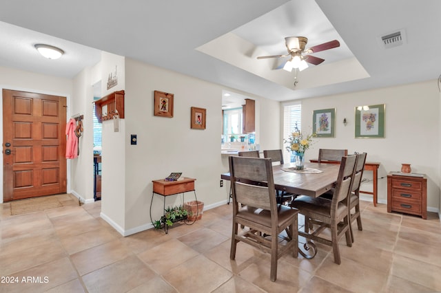 dining room featuring a tray ceiling, ceiling fan, and light tile patterned floors