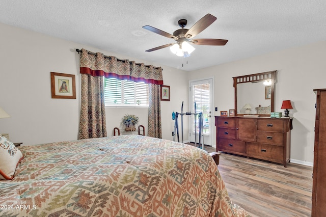 bedroom featuring ceiling fan, light hardwood / wood-style flooring, and a textured ceiling