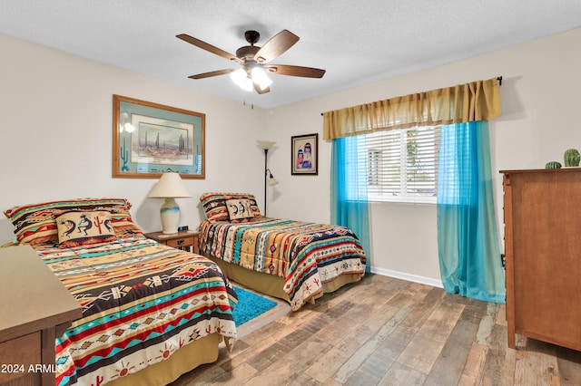 bedroom with ceiling fan, wood-type flooring, and a textured ceiling