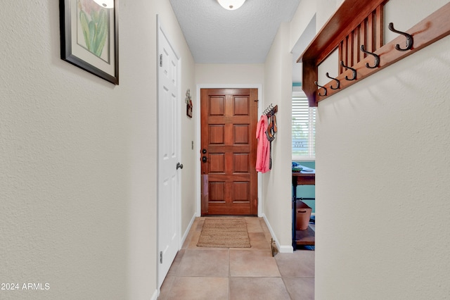 entryway with light tile patterned floors and a textured ceiling