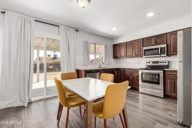 kitchen featuring appliances with stainless steel finishes, backsplash, light countertops, and light wood-style flooring