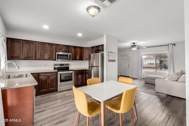 kitchen featuring visible vents, light wood-style flooring, stainless steel appliances, light countertops, and a sink