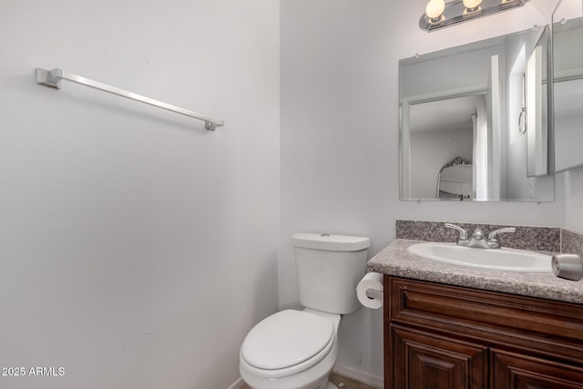 half bathroom featuring toilet, baseboards, and vanity