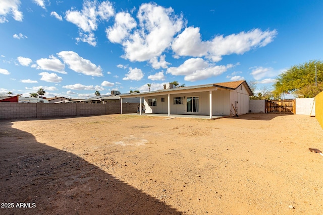 back of property with a patio area, a fenced backyard, and a gate