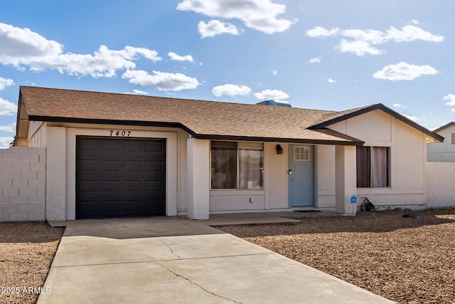 ranch-style home featuring concrete driveway, roof with shingles, and an attached garage