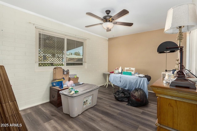 bedroom featuring ceiling fan, brick wall, and dark hardwood / wood-style flooring