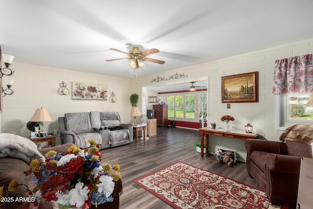 living room with brick wall, dark hardwood / wood-style floors, and ceiling fan