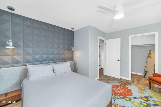 bedroom with hardwood / wood-style flooring, a walk in closet, ceiling fan, and a closet