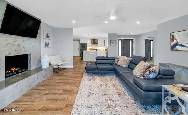 living room with ceiling fan, a fireplace, and hardwood / wood-style floors