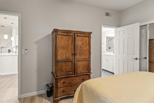 bedroom with light hardwood / wood-style floors, ensuite bath, and a closet