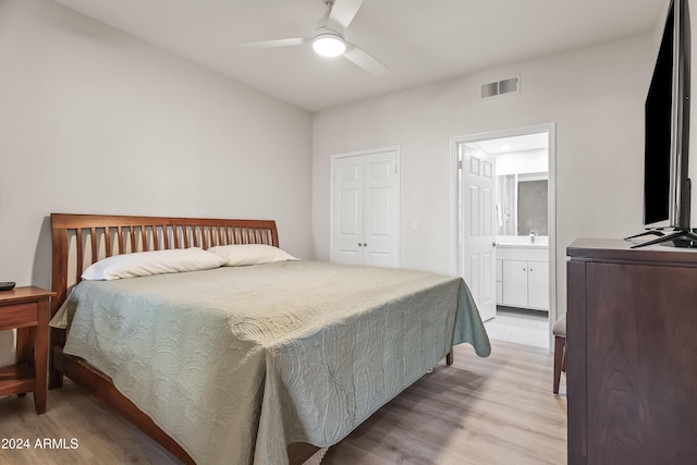 bedroom featuring connected bathroom, light hardwood / wood-style floors, a closet, and ceiling fan