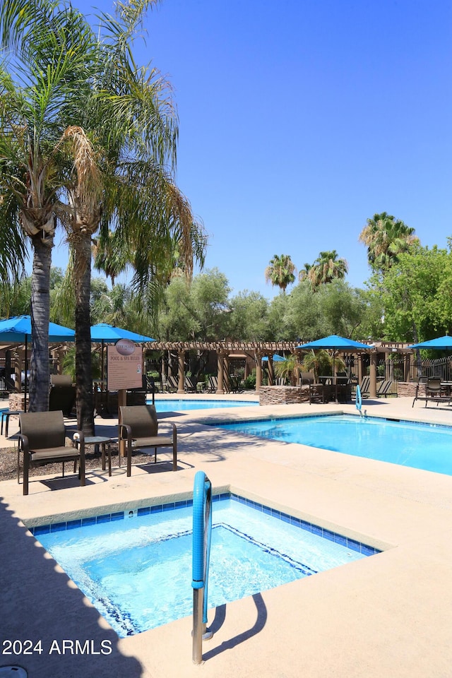 view of swimming pool with a patio area and a community hot tub